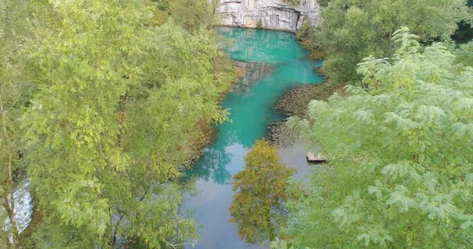 Aerial view of blue waters of Krupa river under rock wall amidst dense greenery in Semic, Slovenia.