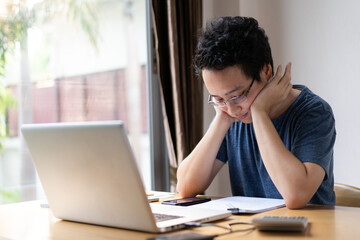 Unhappy Asian young man working at his home portrait. 