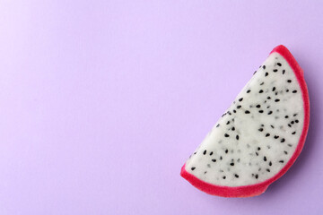 Slice of delicious dragon fruit (pitahaya) on violet background, top view. Space for text