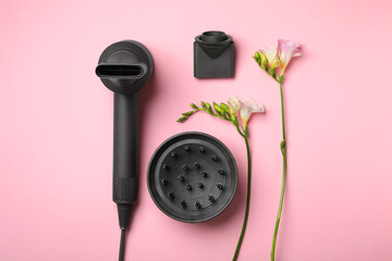 Hair dryer with different attachments on pink background, flat lay. Professional hairdresser tool