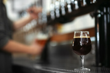 Glass of cold tasty dark beer on bar counter, space for text
