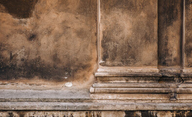 Texture of an antique wall with a portico and a fragment of a column. Vintage background with cracked beige and brown stucco, copy space.