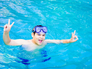 summer holidays and teenage concept - close up of male hand showing v-sign with fingers in the ocean transparent water.