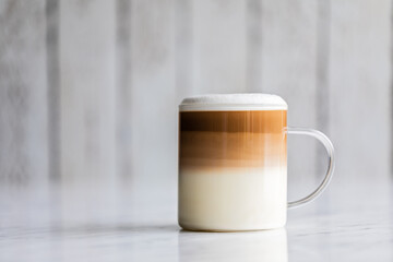 Cafe latte macchiato layered coffee in a see through glass cup on white background. - obrazy, fototapety, plakaty