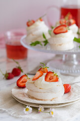 Mini pavlova meringue nests with whipped cream and fresh strawberries.