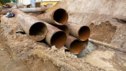 Fragments of old large water pipes. After many years of operation, corroded metal pipe destroyed. Rusty steel tube with holes metal corrosion. Selective focus.