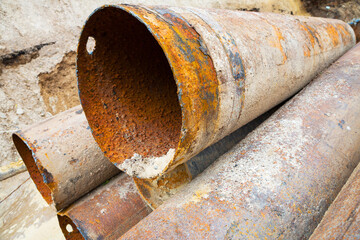 Fragments of old large water pipes. After many years of operation, corroded metal pipe destroyed. Rusty steel tube with holes metal corrosion. Selective focus.