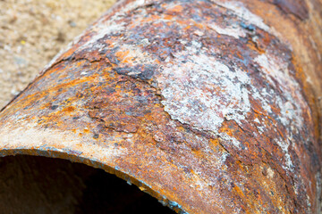 Fragments of old large water pipes. After many years of operation, corroded metal pipe destroyed. Rusty steel tube with holes metal corrosion. Selective focus.