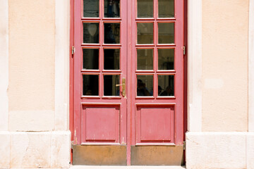 Fototapeta na wymiar Old red doors with windows in the door with white walls.