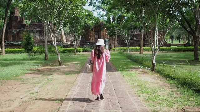 asian woman walking on walkway to "Muang Singha" ancient ruin temple in Kanchanaburi, Thailand.