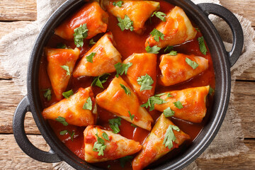 Stuffed cabbage leaves with minced meat and rice in tomato sauce close-up in a bowl on the table. Horizontal top view from above