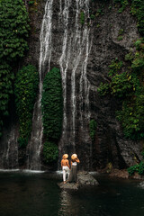 Lovers at the waterfall. Couple admiring a beautiful waterfall in Indonesia. Couple on vacation in Bali. Honeymoon trip. The couple is traveling in Asia. Vacation on the island of Bali with copy space