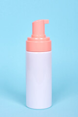 Face foam dispenser bottle, cosmetic lotion. Isolated on blue background.