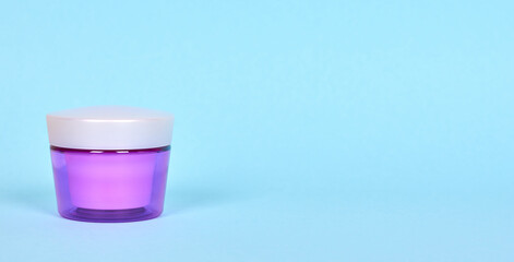 Skin care cream in purple container. Isolated on blue background, copy space template, banner.