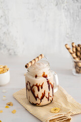 Milkshake mason jar with caramel  on white wooden background.