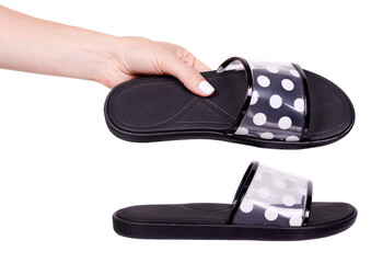 Hand with black slippers with dotted pattern, isolated on white background.