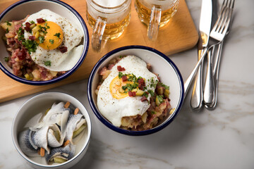Norddeutscher Hamburger Labskaus mit Rindfleisch Corned Beef, Rote Beete, Kartoffeln, Saure Gurken, Spiegelei, Rollmops und Bier auf Marmor