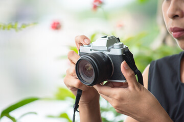 Hand woman holding the camera Taking pictures Background blurry trees .