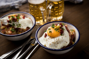 Norddeutscher Hamburger Labskaus mit Rindfleisch Corned Beef, Rote Beete, Kartoffeln, Saure Gurken, Spiegelei, Rollmops und Bier auf Holztisch