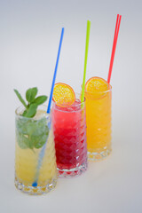 Three tropical mixed drinks with lime and lemon and mint leaves served in different glasses isolated on white.