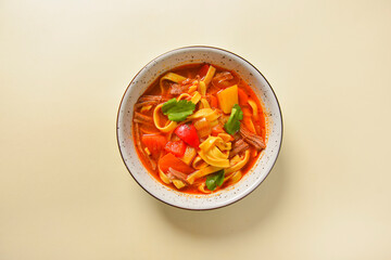 Bowl of minestrone pasta soup, served in a white bowl over bright pastel yellow background. Copy space design banner.