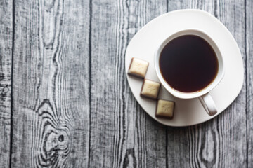 White cup with coffee on a white saucer on a gray wood background