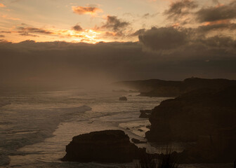 Dramatic scene in the evening, waves coming to shore at sunset, with the coastline made of cliffs in the background