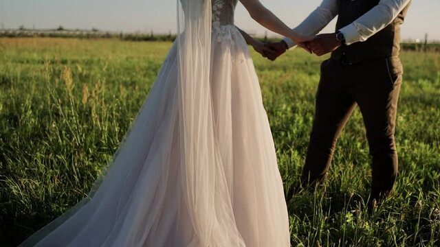 the bride and groom walk across the field sunset