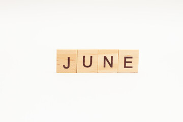 Word JUNE made of wooden blocks on white background. Month of year