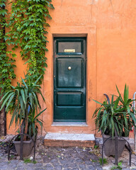 Fototapeta na wymiar vintage house orange facade with green door, Trastevere old neighborhood, Rome Italy