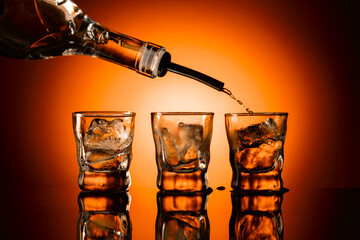 Strong alcohol is poured into glasses with ice.