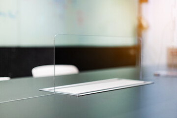Close up of acrylic plexiglass separator standing partition wall with pass-through on the desk in...