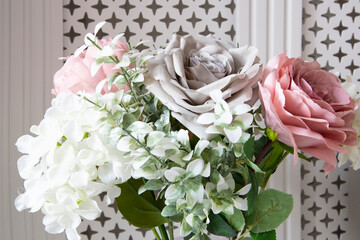 Bouquet of artificial flowers in a vase in front of a white radiator cover
