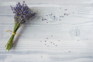 Floral composition. Neat, small bouquet of fresh purple lavender flowers tied with jute thread on a white wooden background with copy space. Minimalist photo. Spring, summer concept. Top view,mock up,