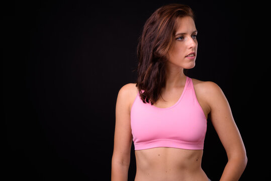 Young beautiful woman ready for gym against black background