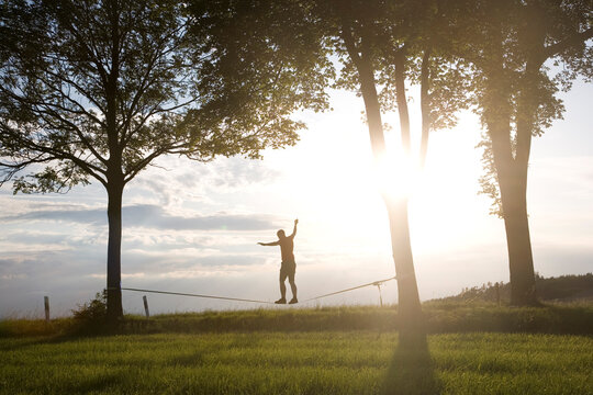 junger Mann auf der Slackline im Sonnenuntergang