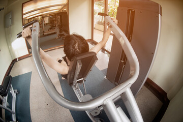 ASian male  doing exercise for chest muscles on pec deck machine during workout in gym.The sport...