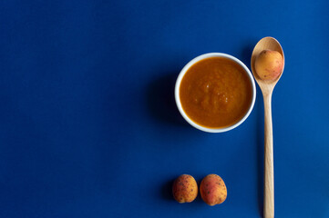 Apricot jam  in white glass jar, witch contains lot of vitamins, carbs, fiber. The recipe is simple – just mix all ingredients such us apricots and sugar, heat to a boil, pureed fruits.