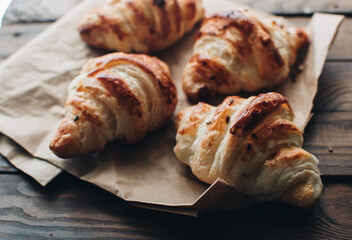 Freshly baked homemade croissants on wooden table, selective focus Fresh out of the oven. Breakfast or brunch concept.
