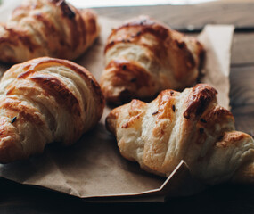 Freshly baked homemade croissants on wooden table, selective focus Fresh out of the oven. Breakfast or brunch concept.