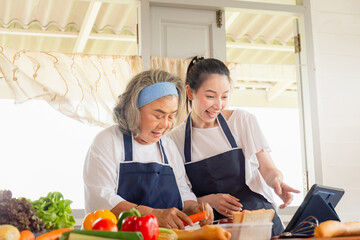 Senior asian mother and middle aged daughter cooking together at kitchen