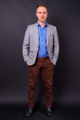 Handsome businessman with blonde hair against black background