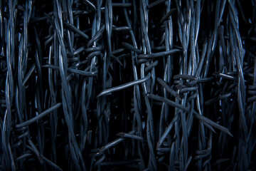 Closeup black barb wire texture background. Vertical dark black barb fence wire abstract background