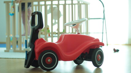 Big red truck and wooden baby cot with baby in.
