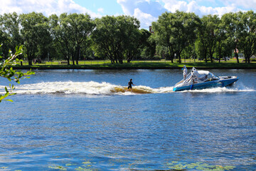 The girl is learning wakesurfing under the guidance of a coach on a boat.