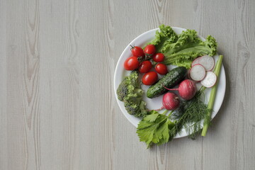 Fresh vegetables in a white plate on a light wooden table