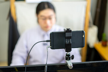 スマートフォンをウェブカメラにしてオンラインミーティングをする若い男性