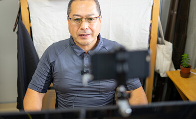 スマートフォンをウェブカメラにして高画質オンラインミーティングをしている笑顔の男性