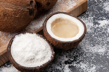 cut fresh coconut with real coconut milk on a dark background of coconut flakes. vitamin fruits. healthy food