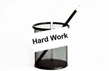 Word hard work on a leaf on a glass for pencils .The concept of working in an office .